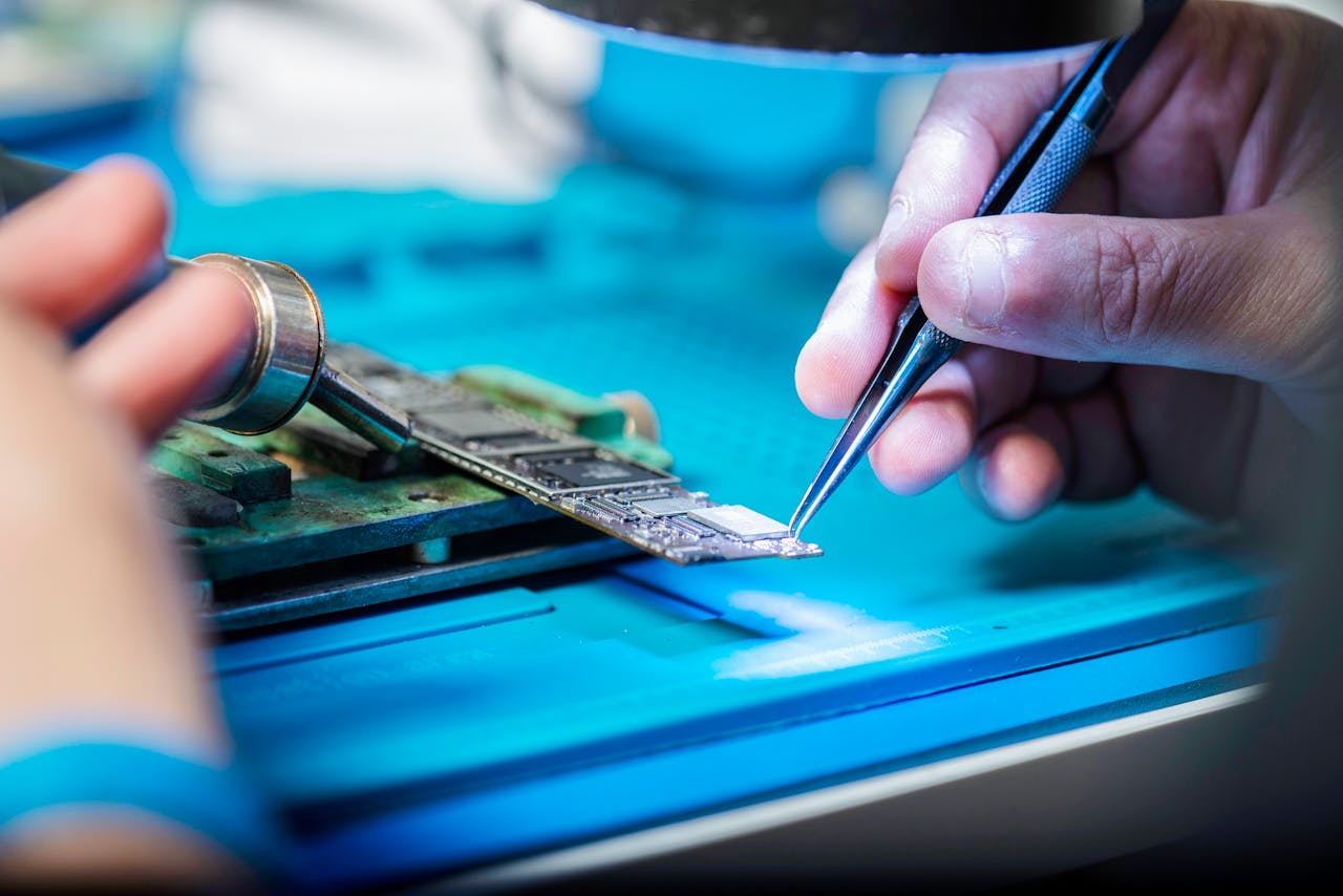 services-01 Hands delicately holding tools repairing a circuit board with precision.
