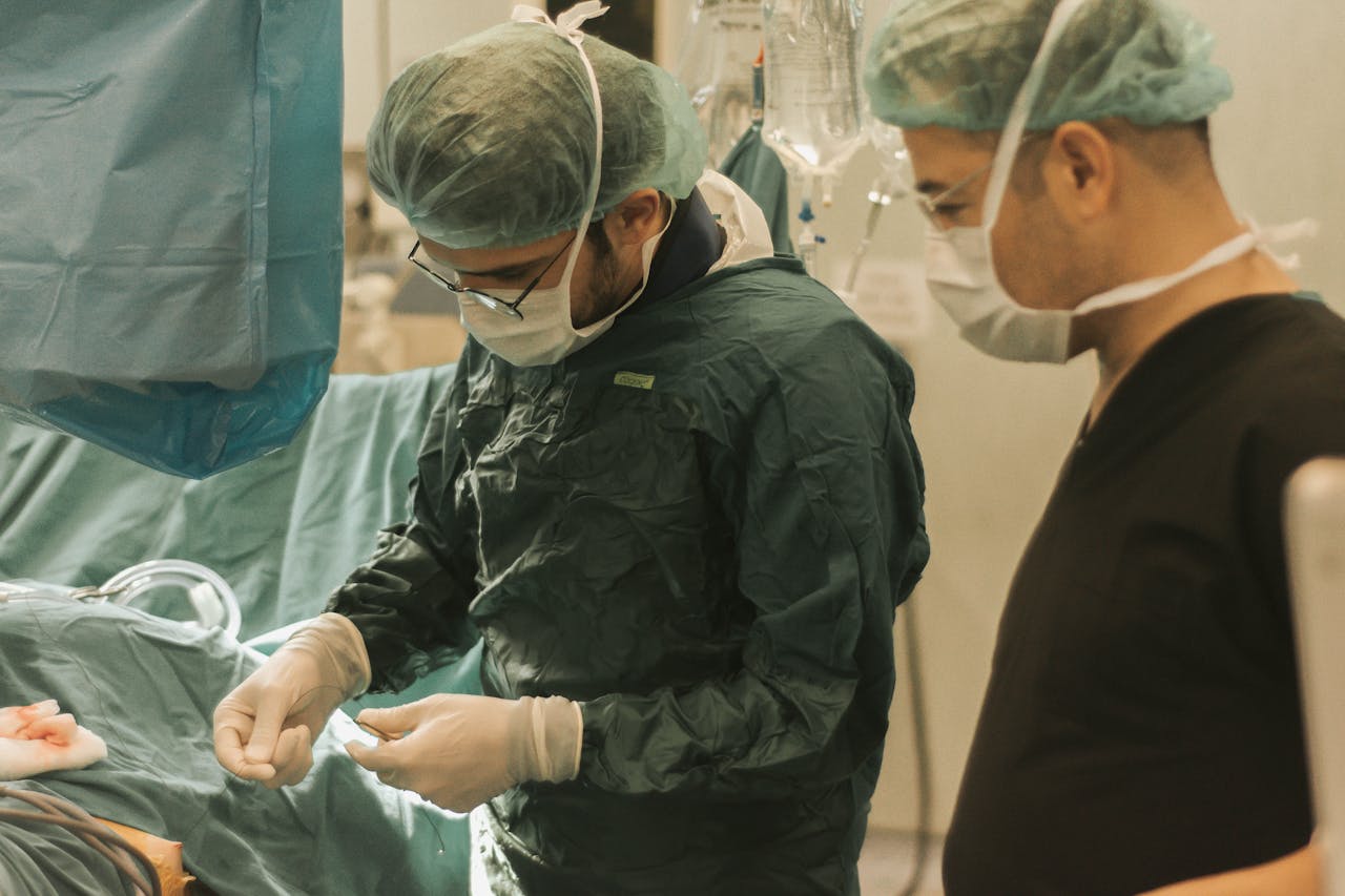 gallery-3 Two surgeons focused on a medical procedure in an operating room, highlighting teamwork in healthcare.