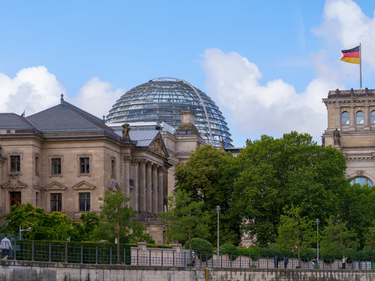 contact-img The Reichstag building in Berlin with the German flag, showcasing iconic architecture.