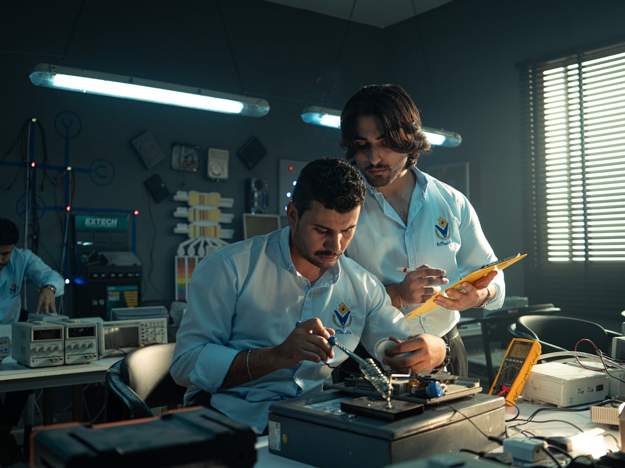 services-02 Two men working on an electronics project in a Baghdad lab, focused and collaborating.