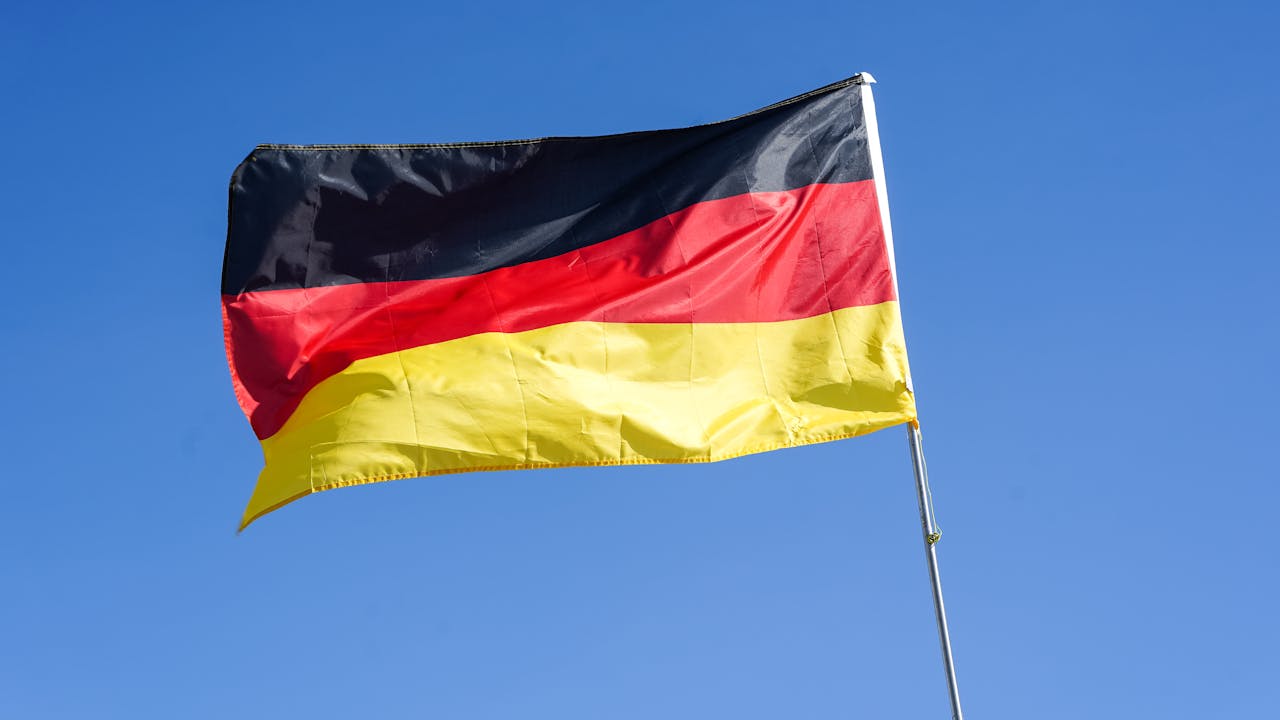 services-img German national flag waving prominently against a bright blue sky in Lüneburg, Germany.