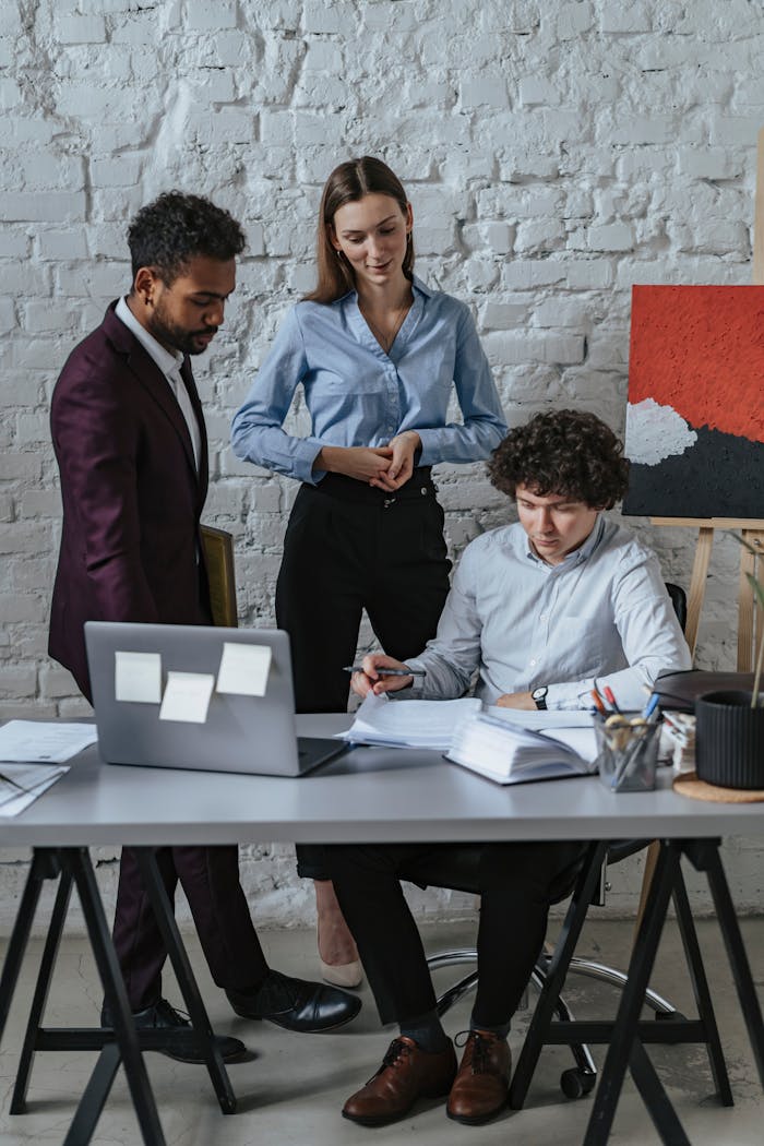 A diverse business team collaborates in a modern office setting, discussing documents and ideas.