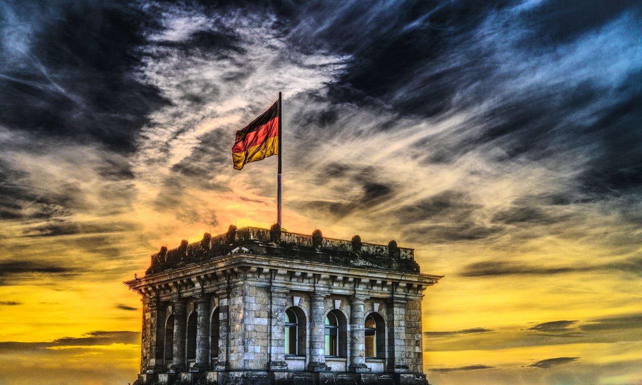 gallery-6 Vibrant sunset over a historic Berlin monument with the German flag waving.