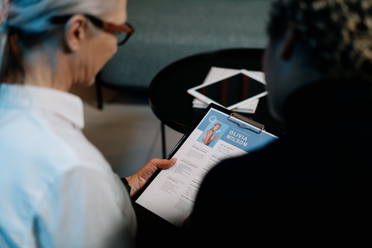 services-03 Business professionals conducting an interview with resume on clipboard in an office setting.